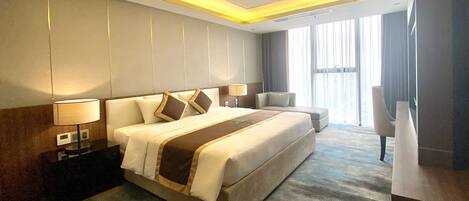 A hotel room with a large bed, bedside tables, a desk, and a chair.