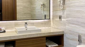 Un baño moderno con un espejo grande, un lavamanos, un secador de pelo y un inodoro.