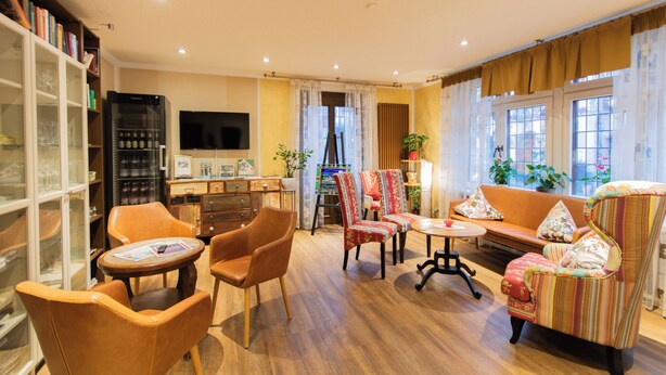 A cozy living room with a sofa, chairs, a coffee table, and a bookshelf. - Hotel Weiler (Oberwesel)