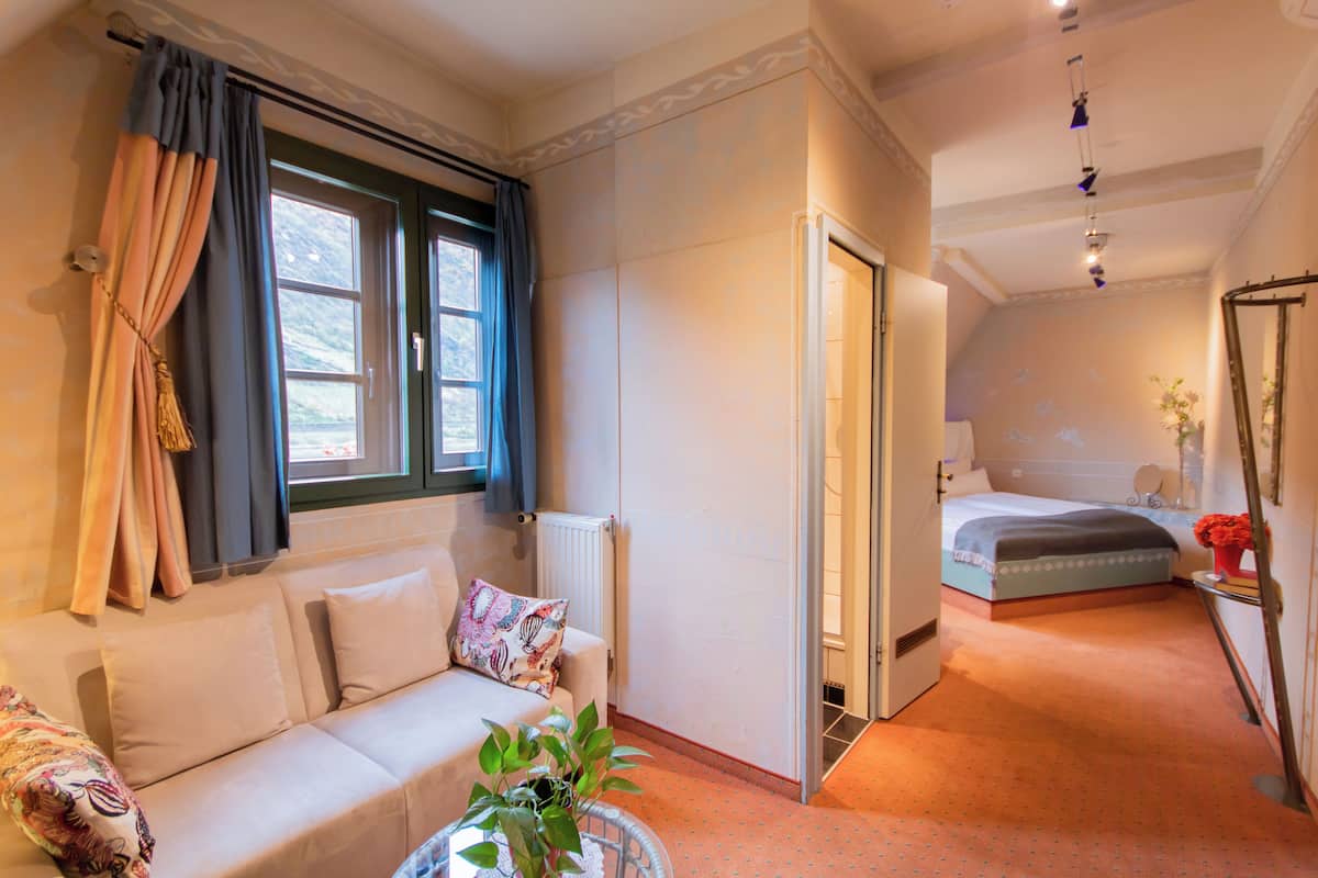 Una habitación de hotel con sofá, cama, una mesita con una planta y un espejo en la pared.