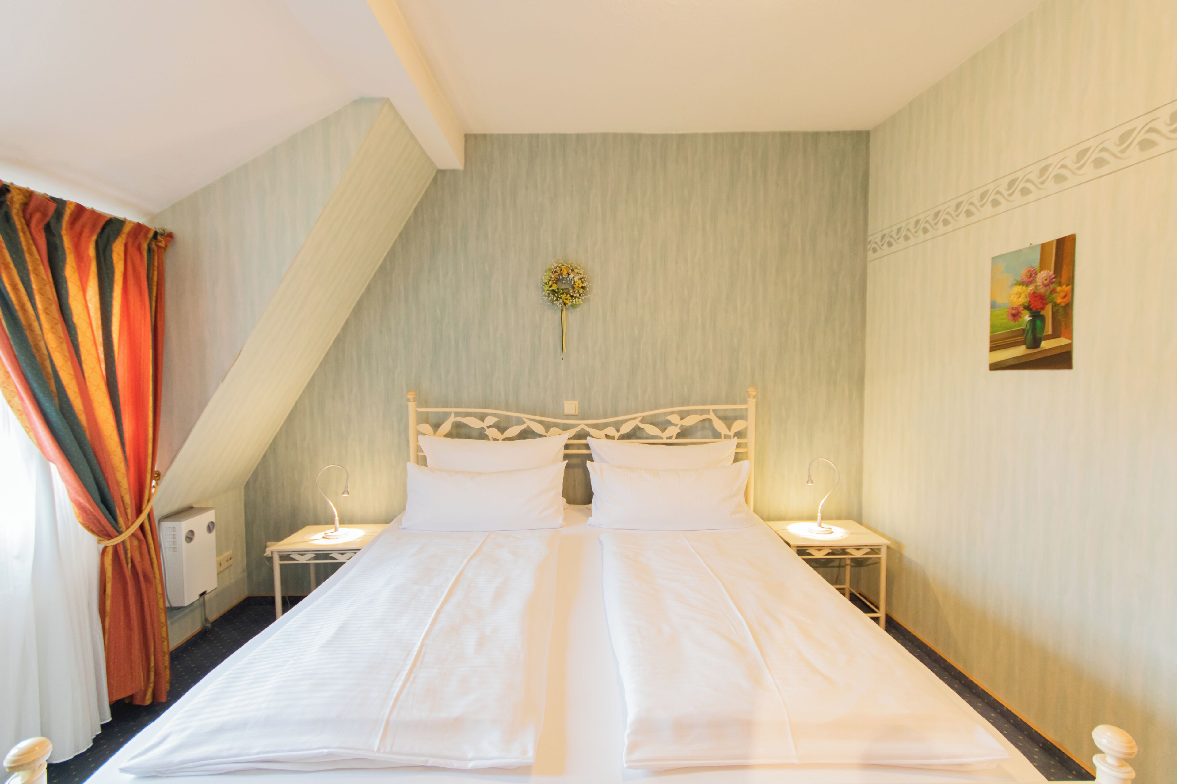 A neatly made bed with white linens, a decorative headboard, and two bedside tables with lamps.