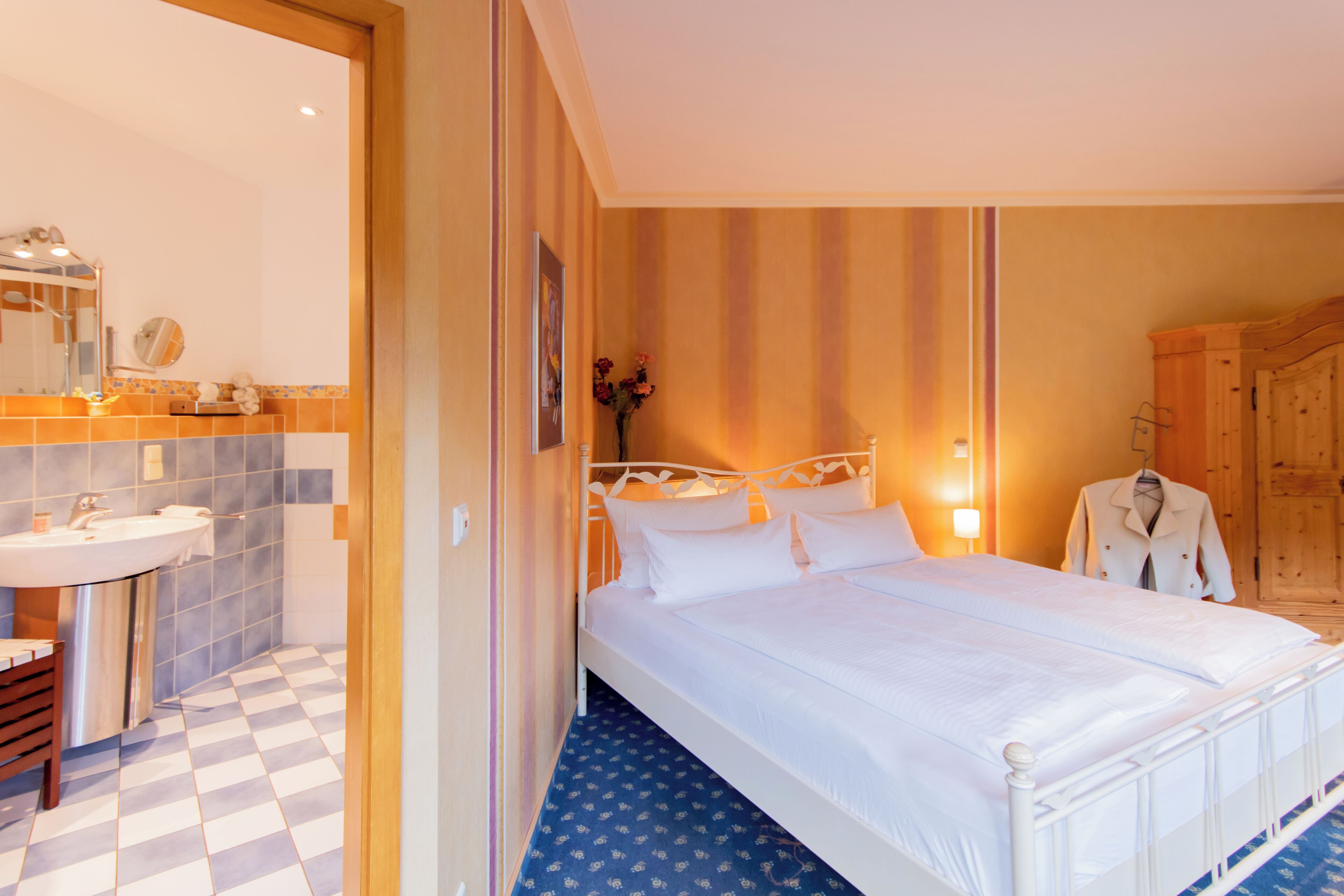 Une chambre d’hôtel comprenant un lit, une salle de bain avec un lavabo et un miroir, et une armoire.