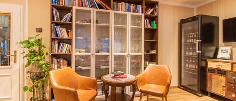 A cozy room with a bookshelf, two leather chairs, a small table, and a refrigerator.