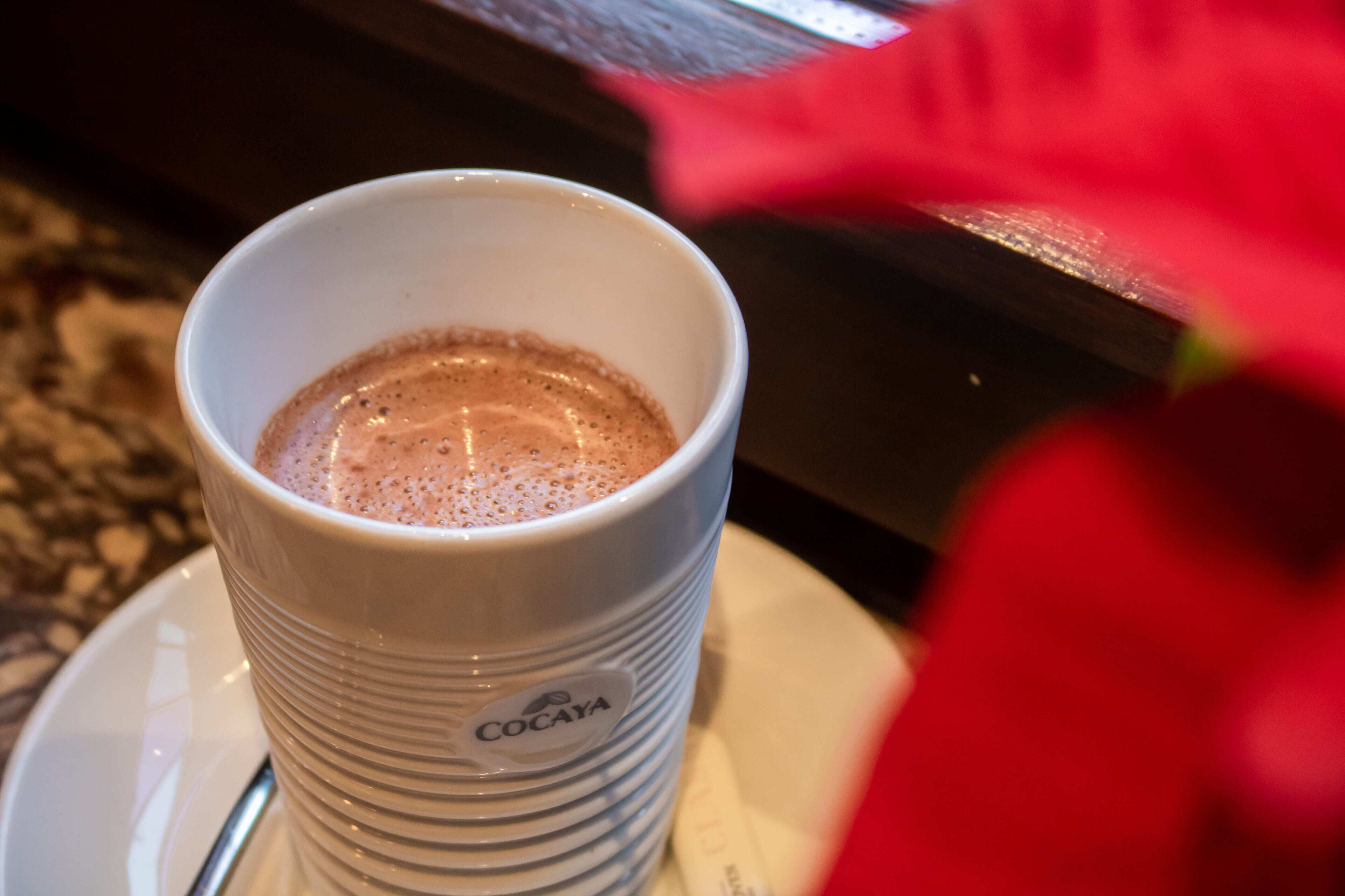 A white cup with a logo, filled with a beverage, on a saucer.