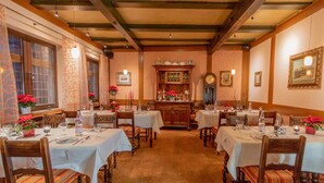 A dining area with multiple tables set for guests, wooden chairs, and a central buffet area. - Hotel Weiler (Oberwesel)