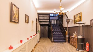 A hallway with patterned flooring, a staircase with blue steps, and a white radiator. - Hotel Weiler (Oberwesel)