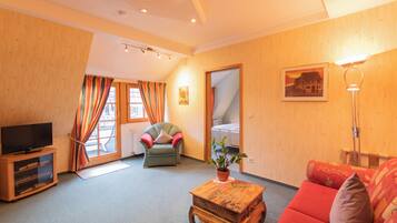 Una sala de estar acogedora con televisor, sofá, sillón y una mesa de centro.