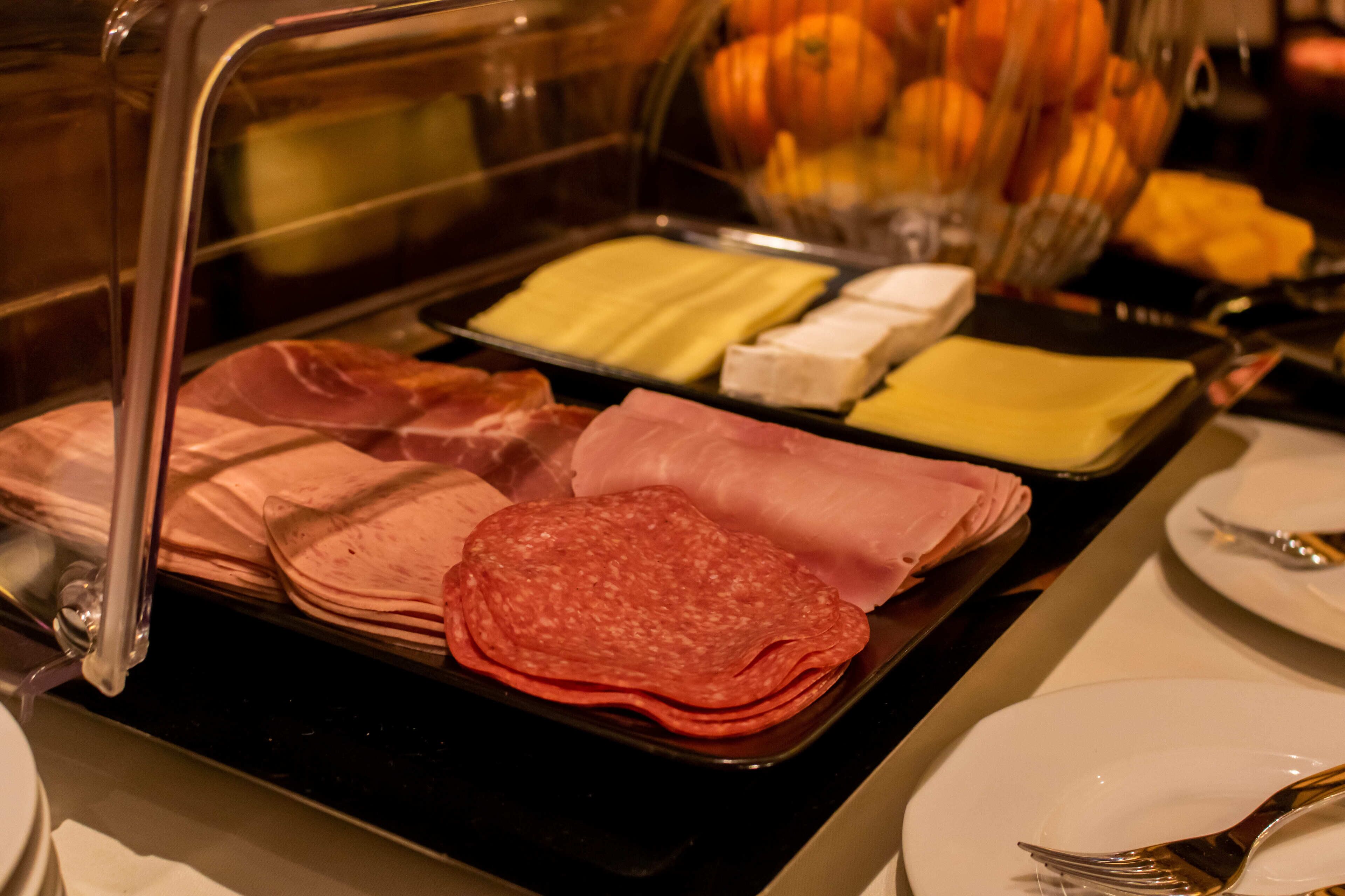 A buffet with various meats and cheeses.