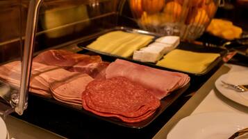 A buffet with various meats and cheeses.