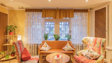 Una sala de estar acogedora con un sofá, dos sillones, una mesa de centro y una ventana con cortinas.