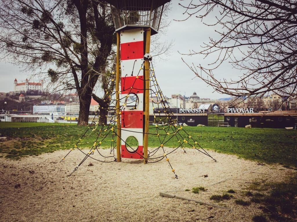 A red and white striped pole with yellow ropes in a park.