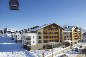 A multi-story hotel with a ski lift in the background, surrounded by snow.