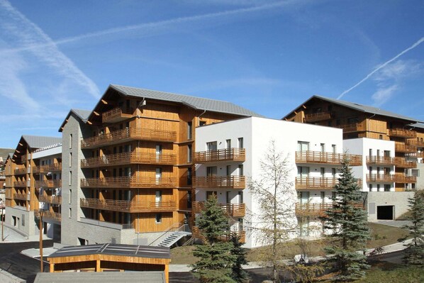 A multi-story hotel with wooden balconies, a ski lift, and a clear sky.