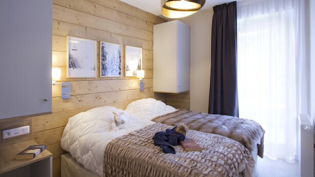 Hotelkamer met twee bedden, een houten hoofdbord, wanddecoratie, een plafondlamp en een raam met gordijnen.