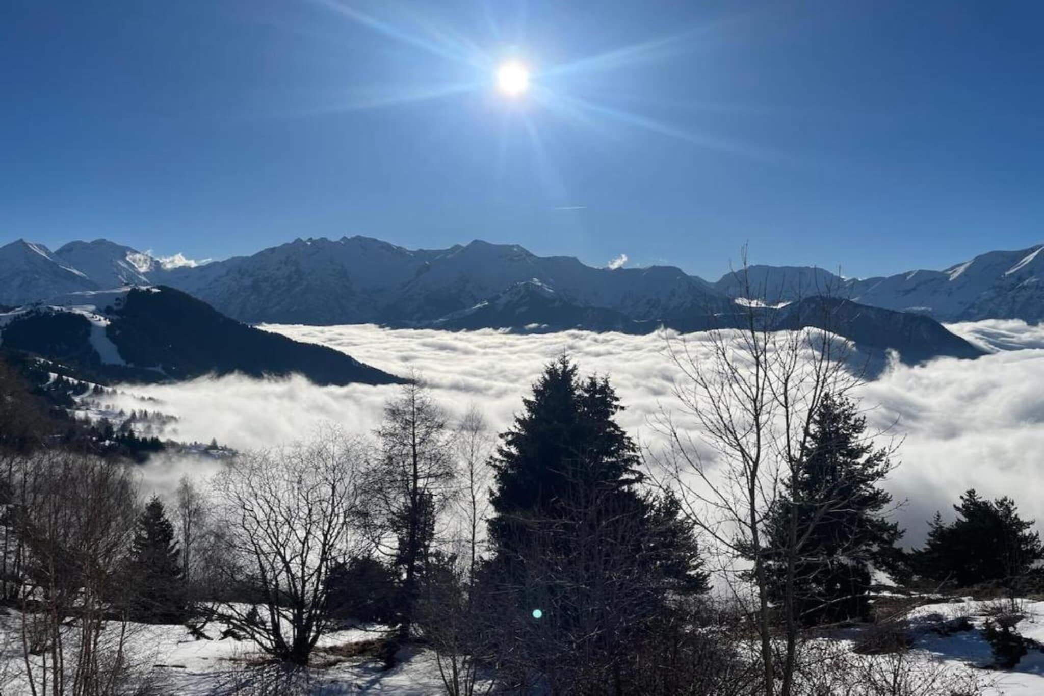 A mountainous landscape with a clear sky and sun shining.