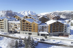 Ein schneebedecktes Bergresort mit mehrstöckigen Gebäuden, Skipisten und freiem Blick auf die umliegenden Berge.