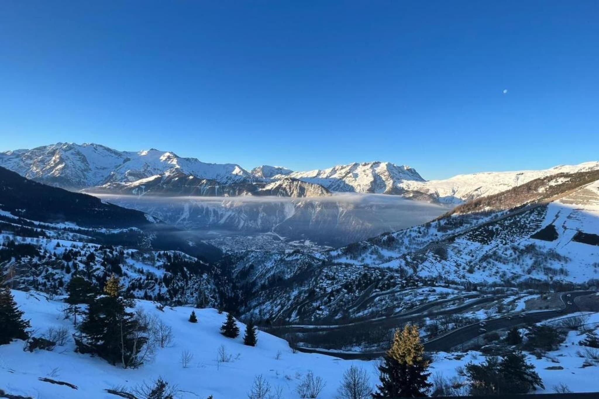 Paisaje montañoso con picos nevados y un valle.