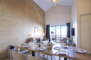 A dining area with a wooden table set for a meal, a sofa, and a television.