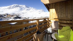En træterrasse med udsigt til et sneklædt bjerg og en by nedenfor.