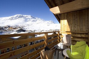 Ein Holzbalkon mit Blick auf einen schneebedeckten Berg und eine Stadt darunter.
