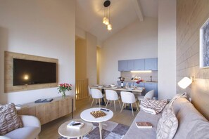 Ein modernes Wohnzimmer mit Flachbildfernseher, einem Essbereich mit Stühlen, einer Küche mit Schränken und einem Kamin.