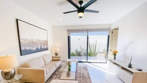 A modern living room with a sofa, ottoman, coffee table, and a ceiling fan. - Unbeatable location 2BD 2BTH Walking distance to Medano... (Cabo San Lucas)