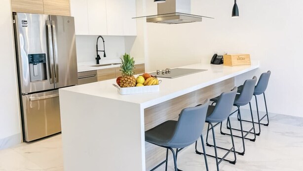 A modern kitchen with a stainless steel refrigerator, a built-in oven, and a large island with bar stools. - Unbeatable location 2BD 2BTH Walking distance to Medano... (Cabo San Lucas)