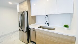 A modern kitchen with a stainless steel refrigerator, a sink, and wooden cabinets. - Unbeatable location 2BD 2BTH Walking distance to Medano... (Cabo San Lucas)