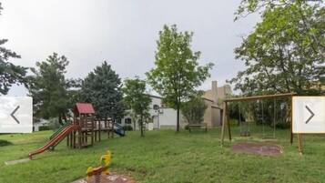 Ein Spielplatz mit Rutsche, Schaukeln und einer Kletterkonstruktion.