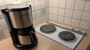 Een keuken met een koffiezetapparaat en een fornuis.