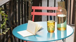 Taula rodona amb un llibre i una ampolla, envoltada de cadires vermelles.