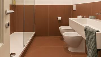 Une salle de bain moderne avec une douche à parois de verre, des toilettes blanches et une baignoire.