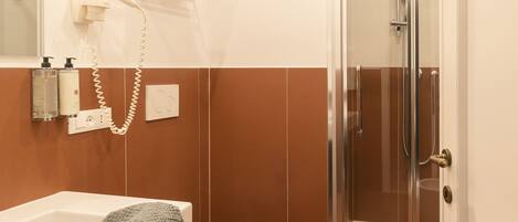 A modern bathroom with a bathtub, toilet, and glass-enclosed shower.
