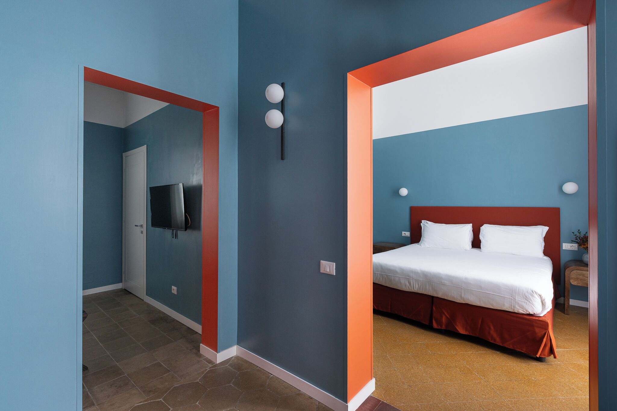 A hotel room with a bed, a TV, and a door leading to another room.