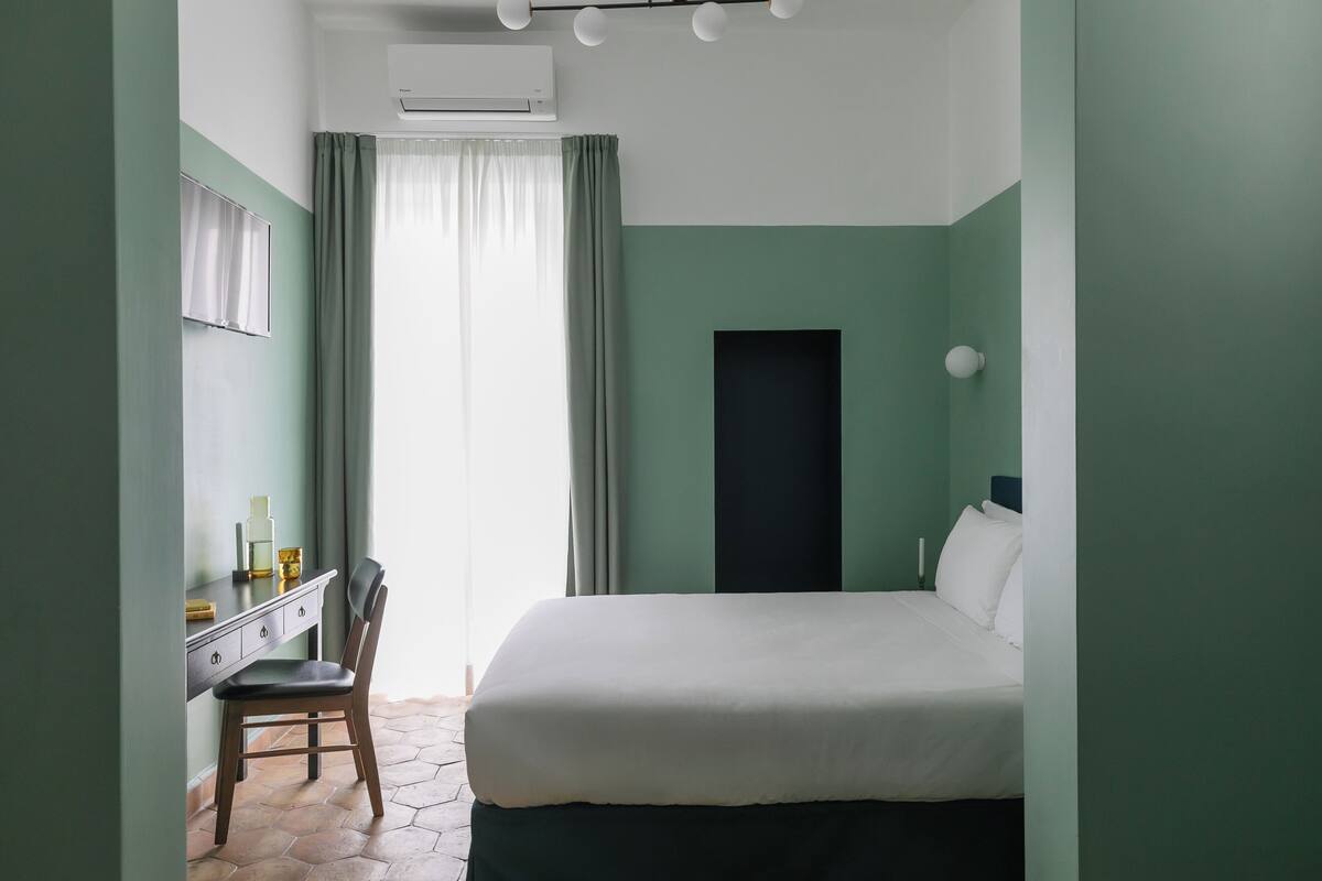 A bedroom with a bed, a desk, and a chair.