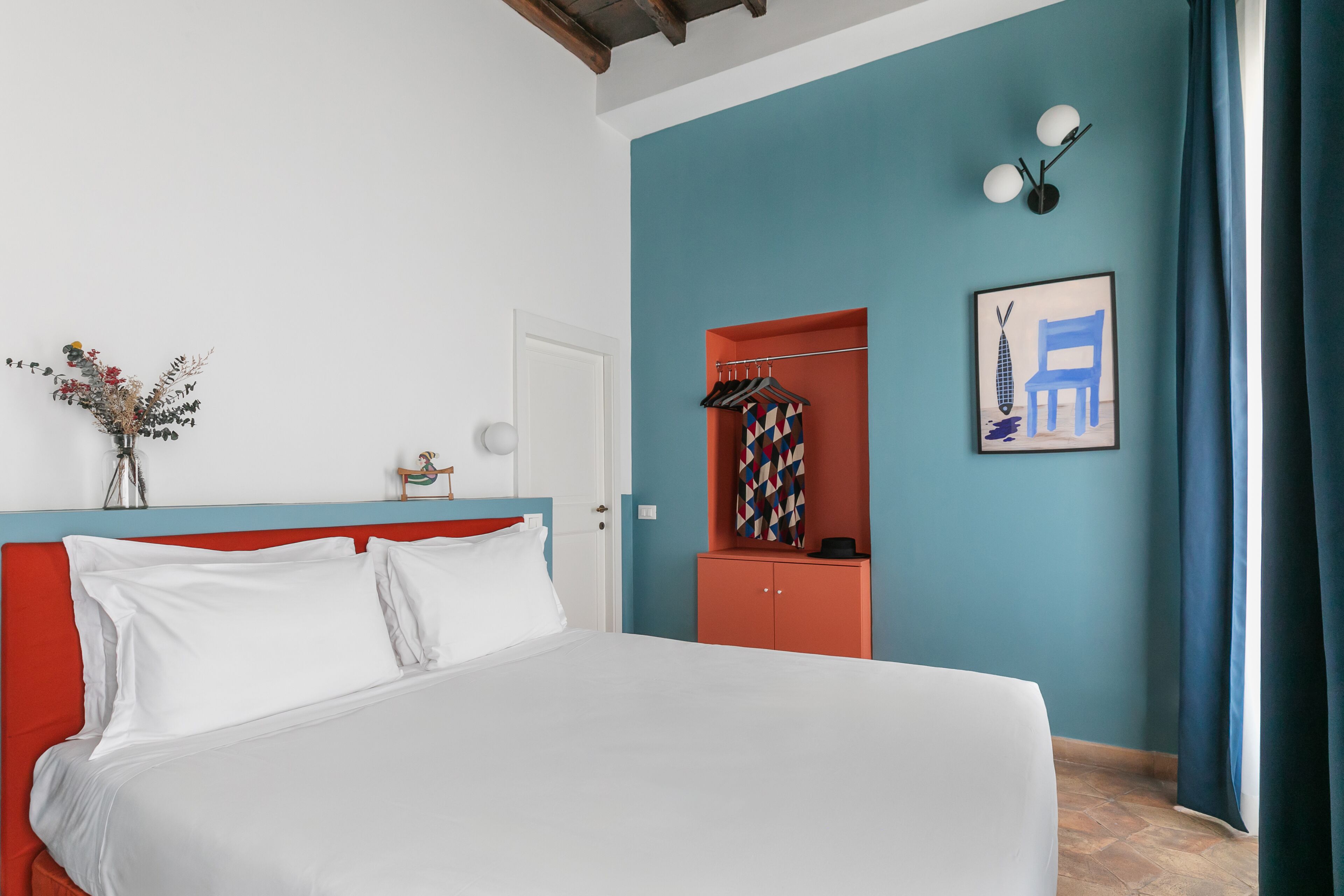 Un dormitorio con cama, armario, puerta y una pared con un cuadro.
