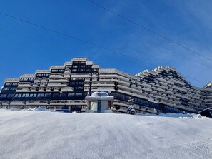 Ein modernes Gebäude mit einem einzigartigen architektonischen Design, das mehrere Balkone und eine zentrale Struktur aufweist.