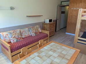 A small, cozy room with a wooden sofa, a microwave, and a wooden cabinet.