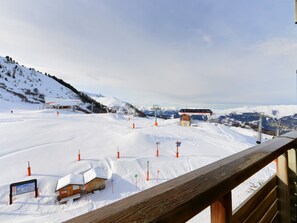 A snow-covered ski slope with a wooden cabin, ski lift, and a mountain view.