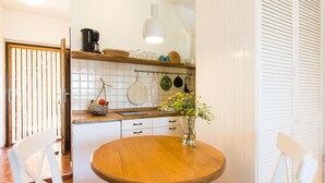 Une cuisine avec une table en bois, des placards blancs et un porte-ustensiles suspendu.