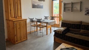A compact living space with a dining area, a sofa, and a wooden cabinet.