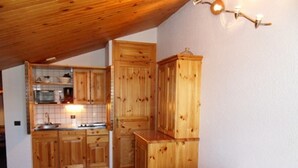 A compact kitchen with wooden cabinets, a microwave, and a sink.