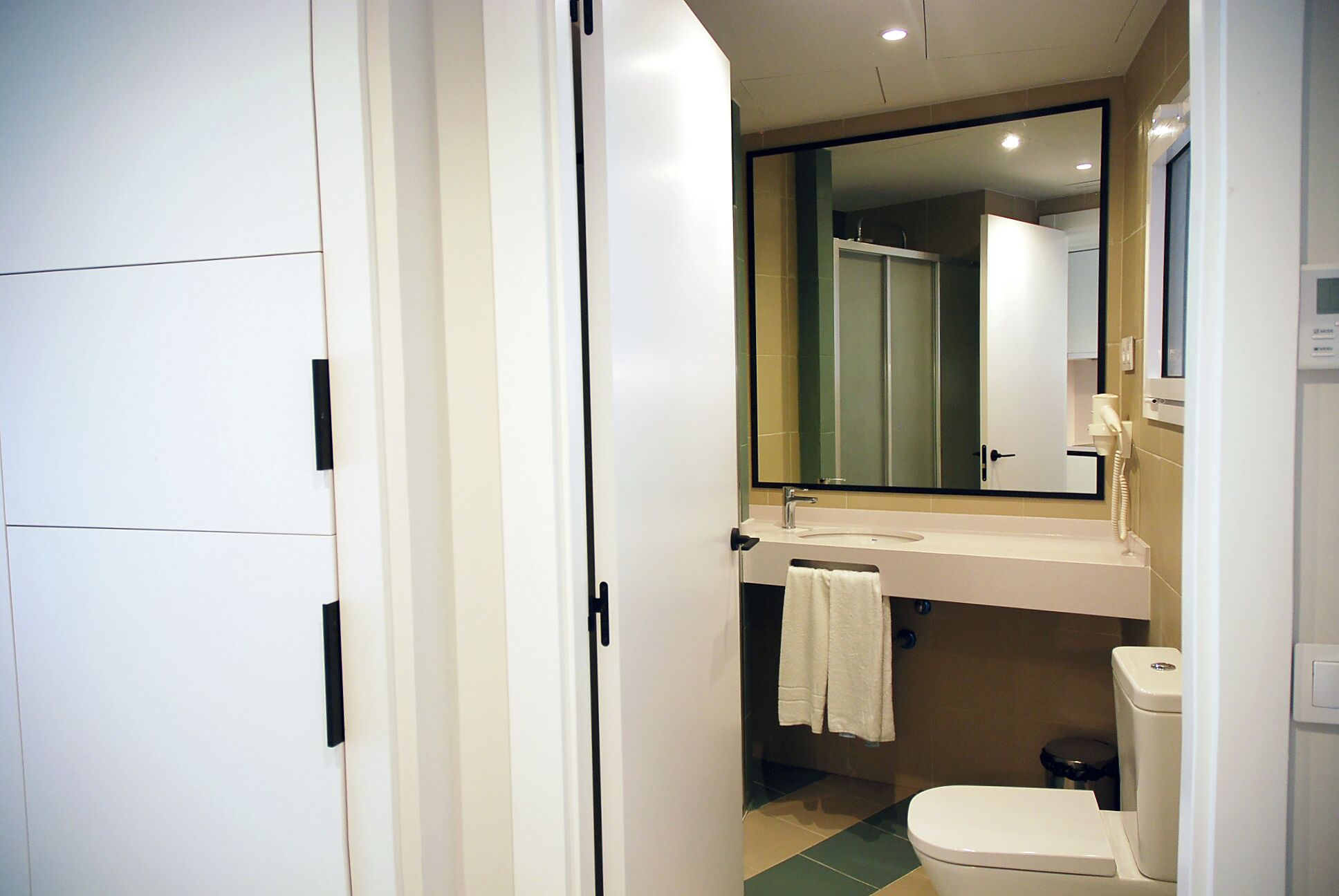 Un baño pequeño con inodoro, lavamanos y espejo.