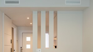 A dining area with a wooden table and white chairs, a door with a window, and a tiled floor. - SUNWAY ATLANTA (Sitges)