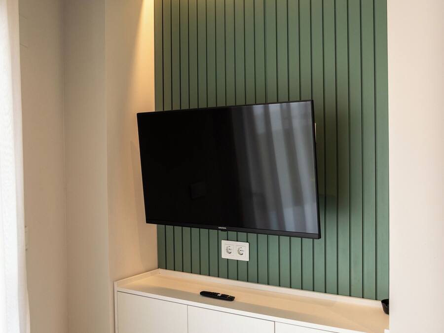 Televisor de pantalla plana montado en una pared con diseño de panel verde.