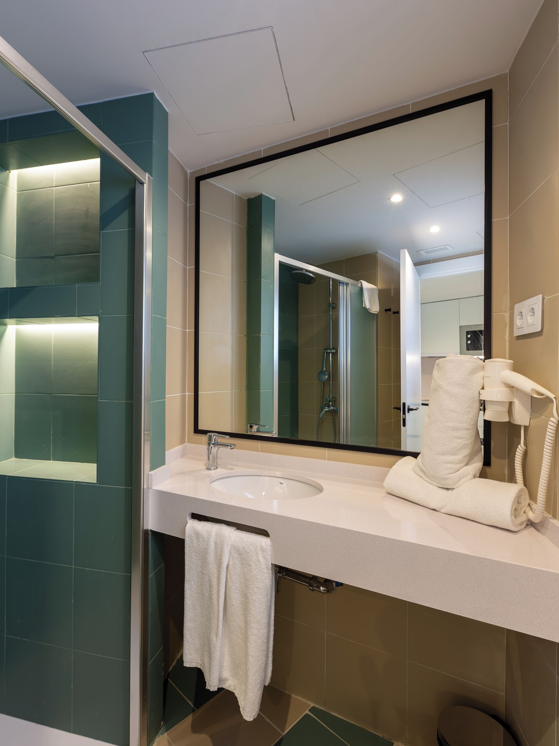 A modern bathroom with a large mirror, a sink, and a towel rack.