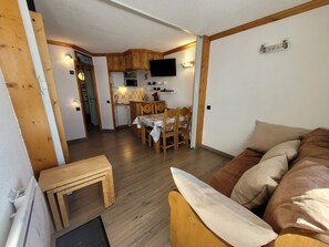 A compact living space with a kitchenette, dining area, and a sofa.