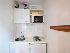 Une cuisine de taille réduite, équipée d’un évier, d’une cuisinière et d’un four à micro-ondes.