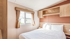 Ein Schlafzimmer mit einem Bett, Vorhängen, einem Fenster und Holzschränken.