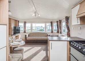 A compact kitchen with a sofa, dining table, and a TV.